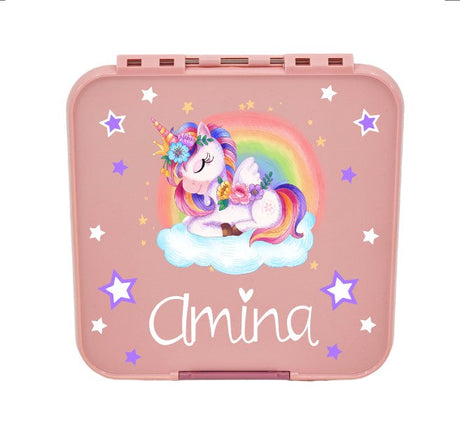 Rosa Kinder Znünibox Lunchbox mit dem Namen „Amina“, verziert mit einem schlafenden Einhorn auf einer Wolke vor einem Regenbogen. Das Einhorn hat bunte Mähne, Flügel und Blumen im Haar. Umgeben ist das Design von weißen und lilafarbenen Sternen.
